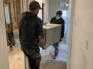 Workers carrying a removed bathroom vanity