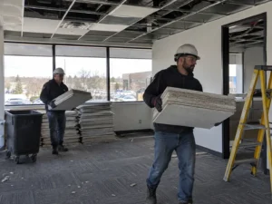 Workers carrying removed office ceiling panels
