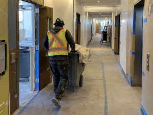 Worker moving debris through an office hallway