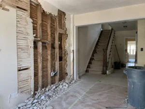 Partly removed plaster and lath beside a protected staircase