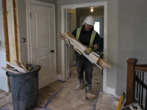 Worker carrying removed trim in a residential hallway